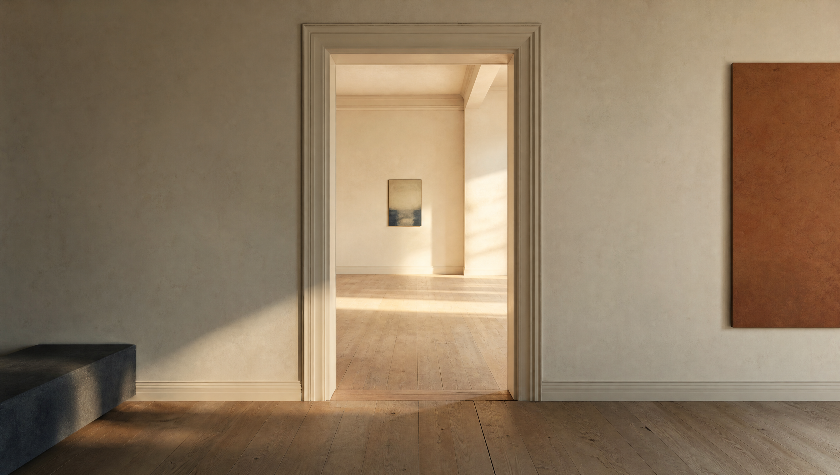 An empty warm gallery with light spilling through a doorway into a further room